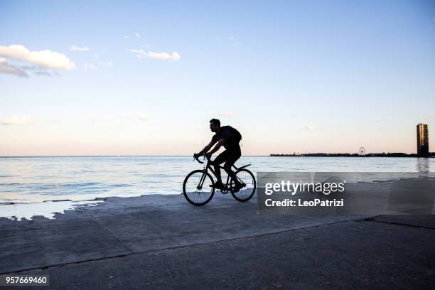 young man cycling in chicago by michigan lake, commuting to work - chicago lifestyle stock pictures, royalty-free photos & images