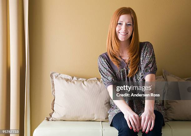 woman on couch smiling - hand op knie stockfoto's en -beelden