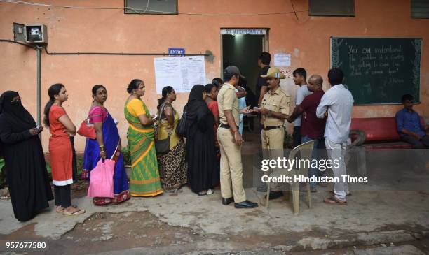 People queue outside a polling booth to cast their vote during the Karnataka State Assembly election at Corporation Girls High School Shivajinagar,...