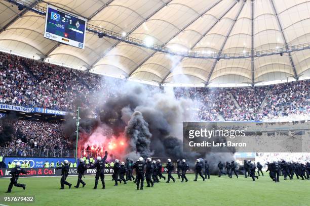 Police are seen as fans throw flares onto the pitch during the Bundesliga match between Hamburger SV and Borussia Moenchengladbach at...