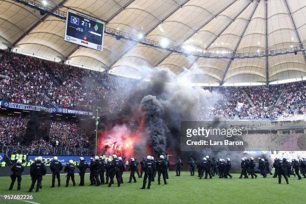 Police are seen as fans throw flares onto the pitch during the Bundesliga match between Hamburger SV and Borussia Moenchengladbach at...