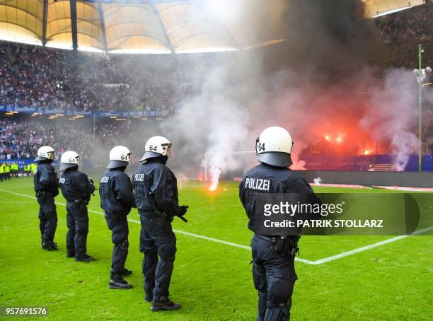 Police stand on the pitch after Hamburg supporters throw fireworks ahead the final whistle of the German first division Bundesliga football match...