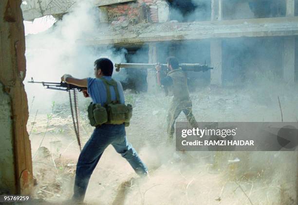 Two militiamen from Amal, the first political organization of Lebanon's Shi'ite Moslems, fire a bazooka and a machine gun 11 September 1989 in the...