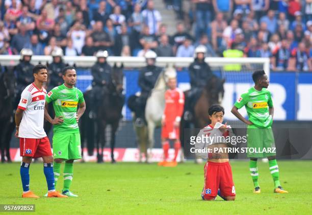 Players of Moenchengladbach and Hamburg wait as mounted police stands on the pitch after Hamburg supporters throw fireworks during the German first...