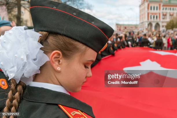 tiener meisje cadet houden van enorme rode vlag banner op "onsterfelijke regiment" processie - victory day russia stockfoto's en -beelden