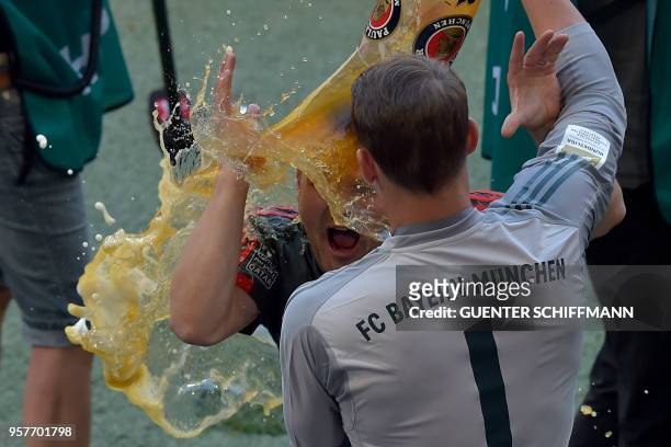 Bayern Munich's German goalkeeper Manuel Neuer douses a teammate with beer as they celebrate their victory at the end of the German first division...