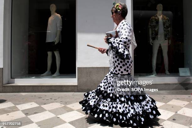 Woman wearing typical dress pass in front of a showcase during the procession of El Rocio.The Romeria del Rocio is one of the most popular...