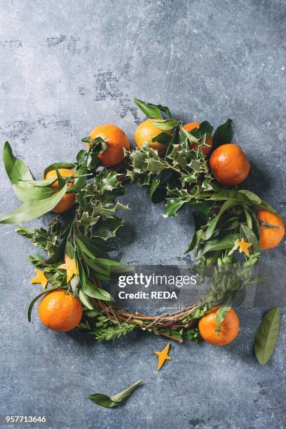 Christmas wreath with clementines tangerines and green branches over blue texture background. Top view, copy space. New Year cards and decorations.