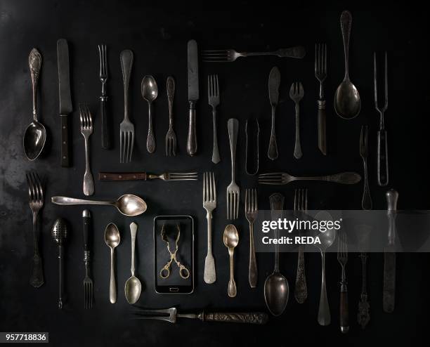 Big set of vintage cutlery with smartphote over black metal..., News Photo