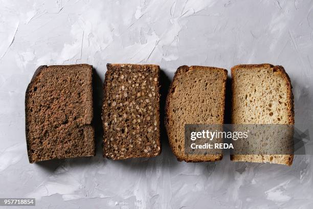 Variety loaves of sliced homemade rye bread whole grain and seeds over gray texture background. Top view. Copy space. Healthy eating.