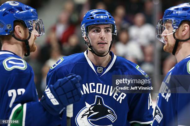 Alex Burrows of the Vancouver Canucks talks to teammates Daniel Sedin and Henrik Sedin during their game against the Nashville Predators at General...