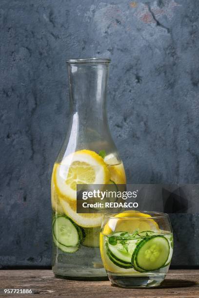 Citrus cucumber sassy sassi water for detox in glass bottle on wooden blue background. Clean eating, healthy lifestyle concept, sunlight.