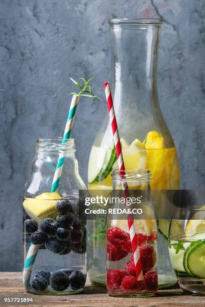 Citrus cucumber berries blueberry and raspberry sassy sassi water for detox in glass bottles with cocktail tubes on wooden blue background. Clean...
