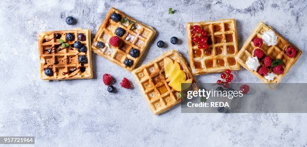 Homemade square belgian waffles with fresh ripe berries blueberry, raspberry, red currant, peach served with caramel, balsamic sauce, honey, whipped...