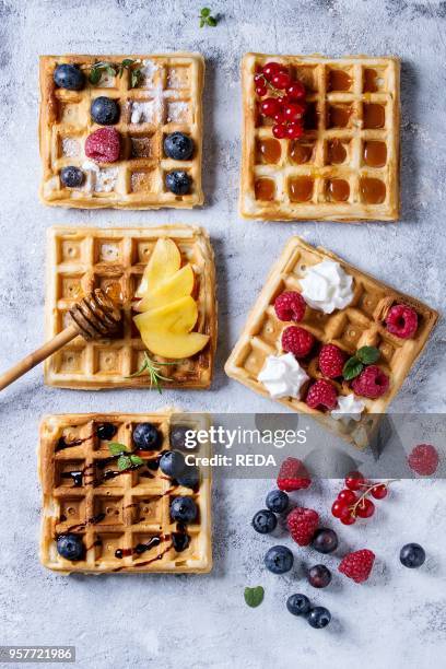 Homemade square belgian waffles with fresh ripe berries blueberry, raspberry, red currant, peach served with caramel, balsamic sauce, honey, whipped...