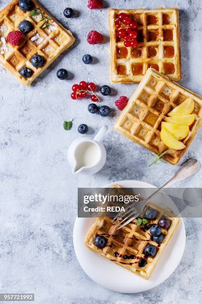 Homemade square belgian waffles with fresh ripe berries blueberry, raspberry, red currant, peach served with caramel, balsamic sauce, honey, whipped...