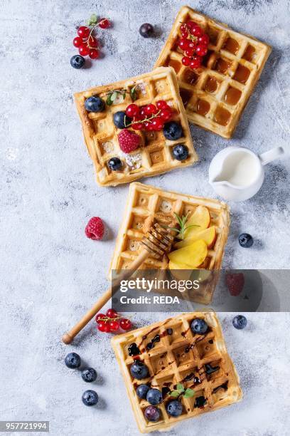 Homemade square belgian waffles with fresh ripe berries blueberry, raspberry, red currant, peach served with caramel, balsamic sauce, honey, whipped...