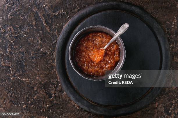 Bowl of red caviar with spoon served on black wooden chopping board over brown texture background. Top view with space.
