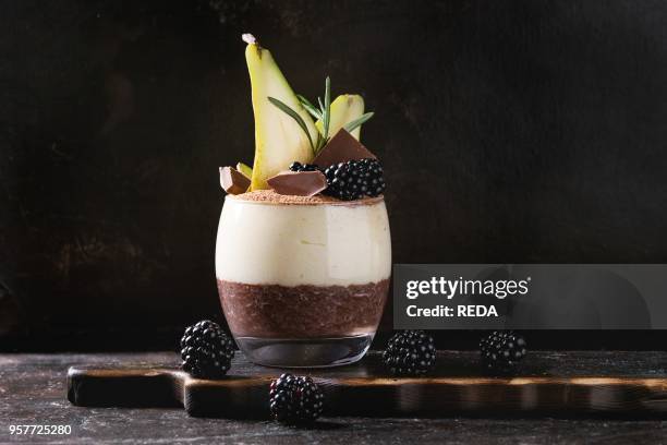 Dessert breakfast layered chia seeds, chocolate pudding, rice porridge in glass decorated by fresh blackberries, pear, cocoa powder. Stand with spoon...