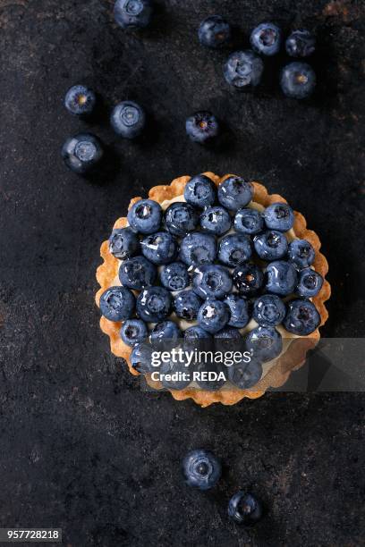 Lemon tartlet with fresh blueberries over black background. Top view. With space for text.