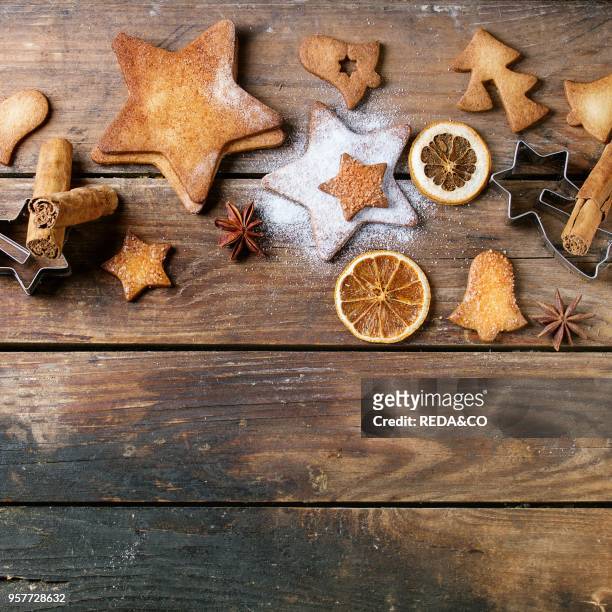 Homemade Christmas shortbread star shape sugar cookies different size with sugar powder, cinnamon and cookie cutters on old wooden surface. Christmas...
