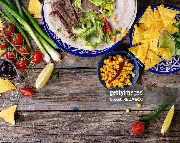 Food background with nachos chips and ingredients for making tartilla and burrito. Onion, tomatoes, chili peppers, beef, tortillas and corn with...