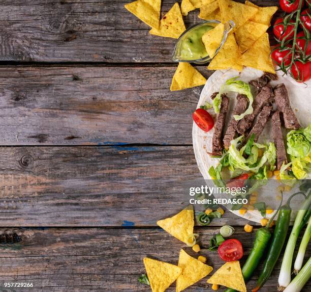 Food background with nachos chips and ingredients for making tartilla. Onion, tomatoes, chili peppers, beef, tortillas and corn with deeps over old...