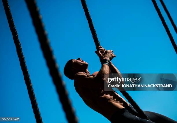 Competitor crosses the Rope Climb obstcale during the Tough Viking race on May 12, 2018 in Stockholm. - The course of the Tough Viking race consists...