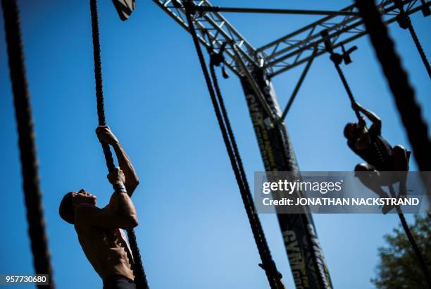 Competitors cross the Rope Climb obstcale during the Tough Viking race on May 12, 2018 in Stockholm. - The course of the Tough Viking race consists...