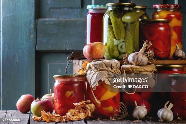 Collection set of many homemade glass jars with preserved food , with garlic and fresh and dried apples. Over old wooden table. Dark rustic style.