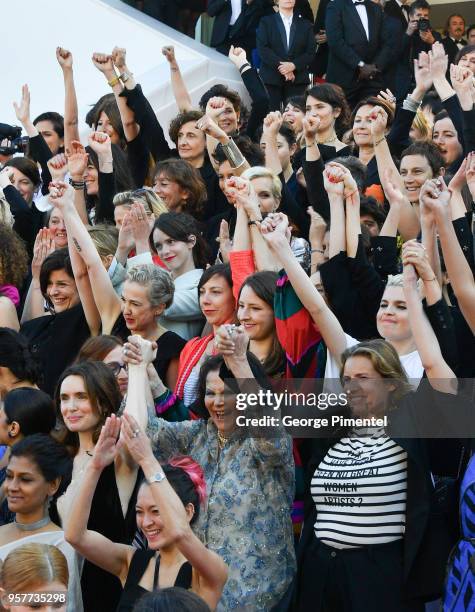 Filmmakers raise their arms as clap after Jury head Cate Blanchett with other filmmakers read a statement on the steps of the red carpet in protest...