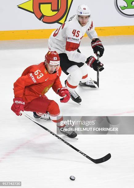 Yevgeni Dadonov of Russia and Michael Fora of Switzerland fight for the puck during the group A match between Russia and Switzerland at the 2018 IIHF...