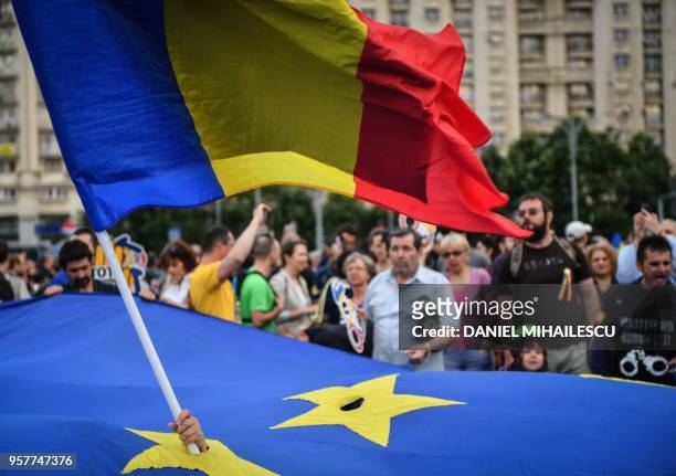Protester holds a national flag through an European flag during a protest asking for the resignation of the Romanian Prime minister on May 12, 2018...