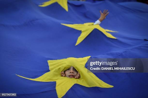 Youth appears through an European flag during a protest asking for the resignation of the Romanian Prime minister on May 12, 2018 in front of the...