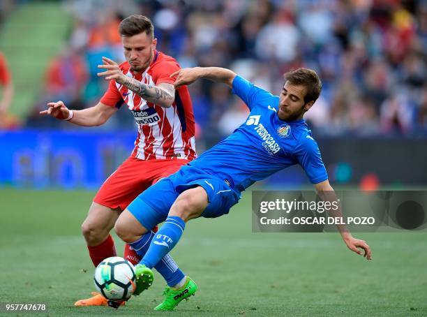 Atletico Madrid's Spanish midfielder Saul Niguez vies with Getafe's midfielder Flamini during the Spanish league football match between Getafe and...