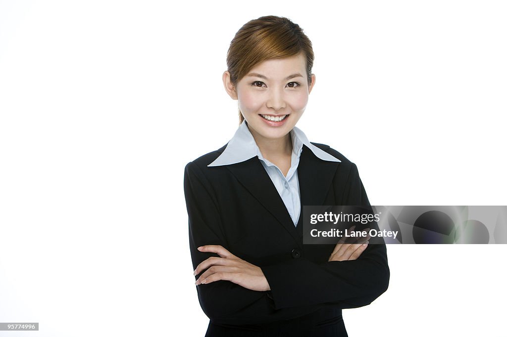 Smiling young businesswoman standing with arms crossed