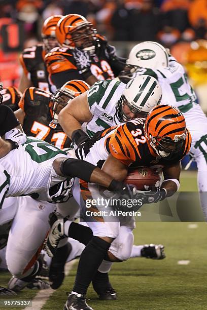 Halfback Cedric Benson of the Cincinnati Bengals is tackled by Linebacker Bryan Thomas and Defensive End Mike DeVito of the New York Jets during...