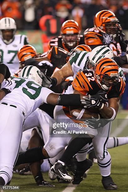 Halfback Cedric Benson of the Cincinnati Bengals is tackled by Linebacker Bryan Thomas and Defensive End Mike DeVito of the New York Jets during...