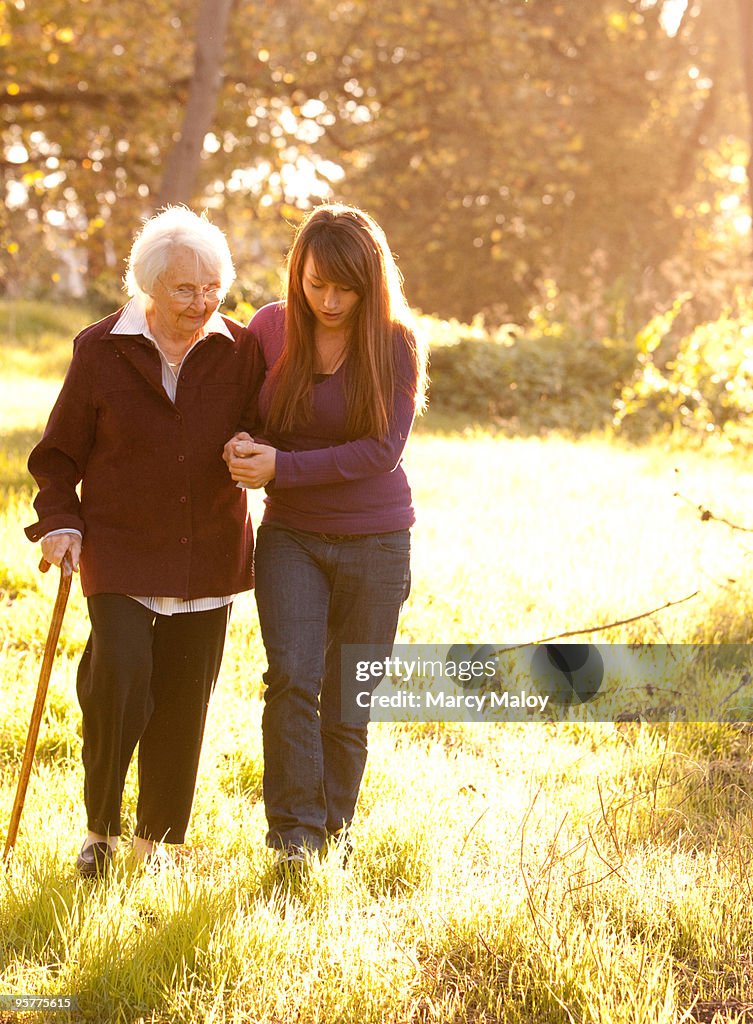 Young Woman helping Older Women walk in woods