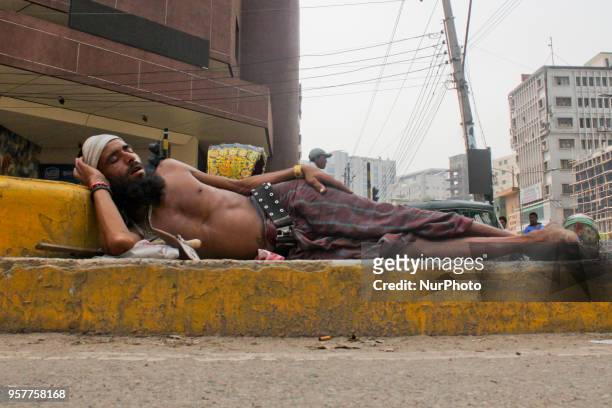 Homeless man is sleeping at the heart of the capital on a road divider hanging a tag where 2 photographs is mention-able one is Bangabondhu himself...