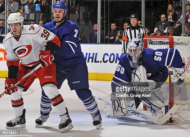 Ian White of the Toronto Maple Leafs battles with Patrick Dwyer of the Carolina Hurricanes as Jonas Gustavsson defends the goal during their NHL game...