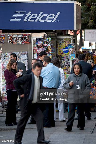 Pedestrians pass by a banner for Telcel, America Movil SAB's Mexican wireless unit, in Mexico City, Mexico, on Thursday, Jan. 14, 2010. Carlos Slim's...