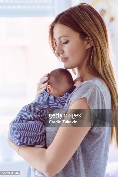 portrait of a beautiful young mother holding her newborn baby - baby blue stock pictures, royalty-free photos & images