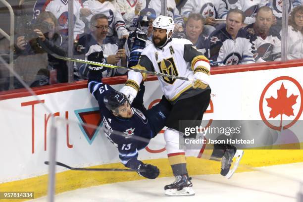 Brandon Tanev of the Winnipeg Jets is checked into the boards by Deryk Engelland of the Vegas Golden Knights during the first period in Game One of...