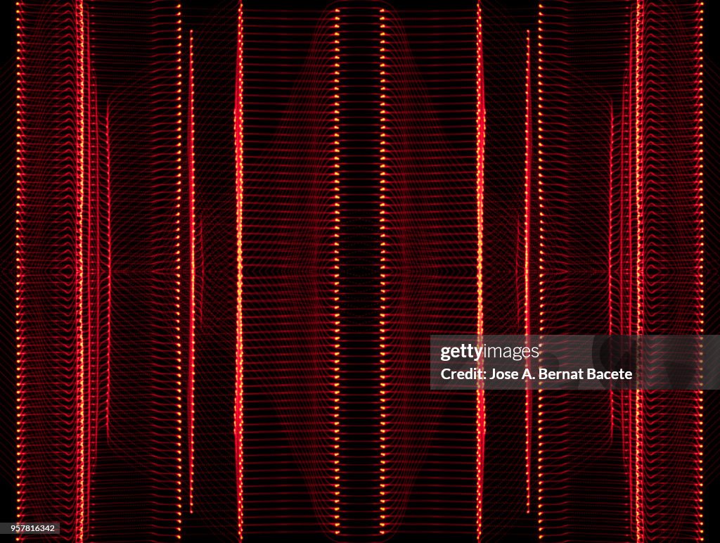 Close-up abstract pattern of intertwined colorful light beams of color red on a  black background.