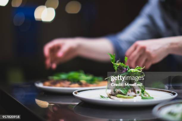 cook preparing many plates in a restaurant kitchen. catering. caterer - fine food stock pictures, royalty-free photos & images