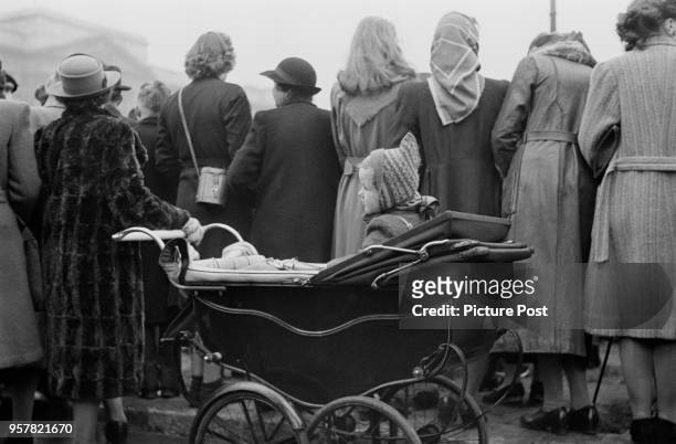 Toddler in a pram among the spectators outside Buckingham Palace to watch the wedding procession of Princess Elizabeth and Philip Mountbatten, Duke...