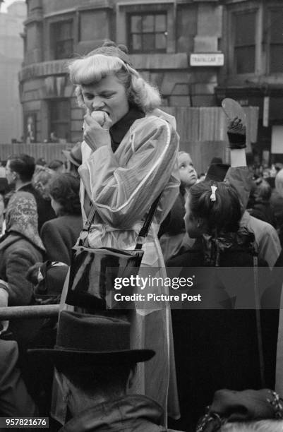 Woman eating an apple among the spectators in Trafalgar Square to watch the wedding procession of Princess Elizabeth and Philip Mountbatten, Duke of...