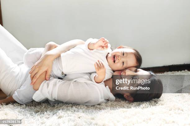 mother and  baby laying on floor - asian baby fotografías e imágenes de stock