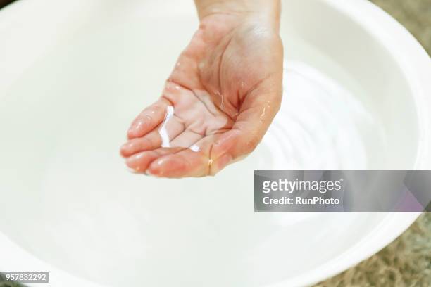 woman placing hand in bowl of water, close-up - testing the water 英語の慣用句 ストックフォトと画像